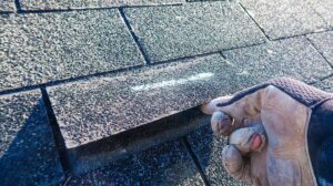 A homeowner using a flashlight to inspect the roof decking inside an attic.